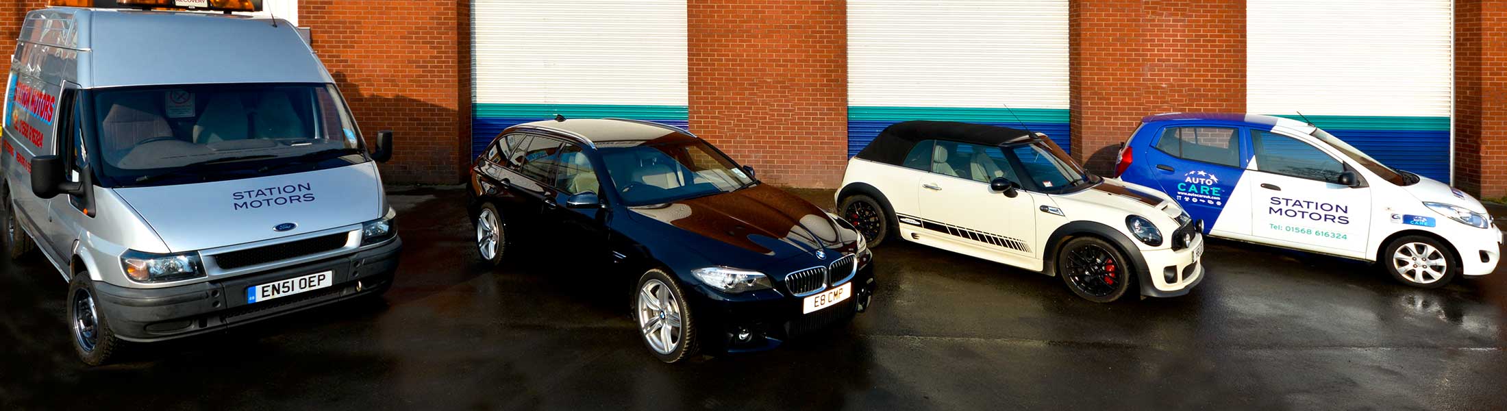 A Transit van, BMW, Mini and the courtesy car lined up outside the workshop